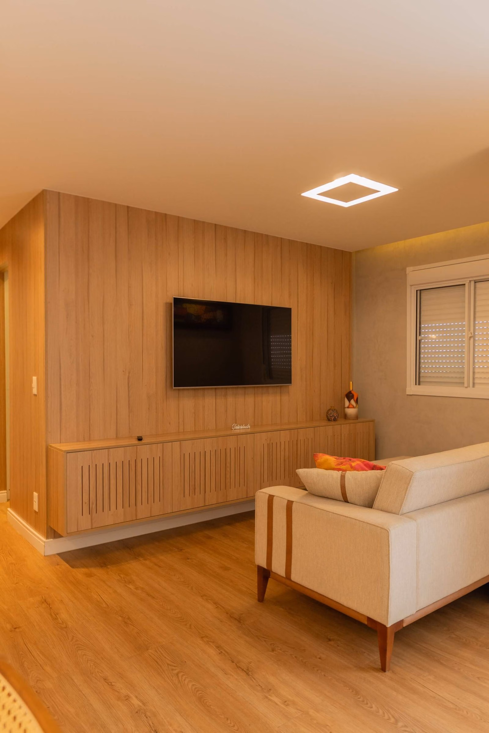 Sala de estar com painel e rack planejados em madeira